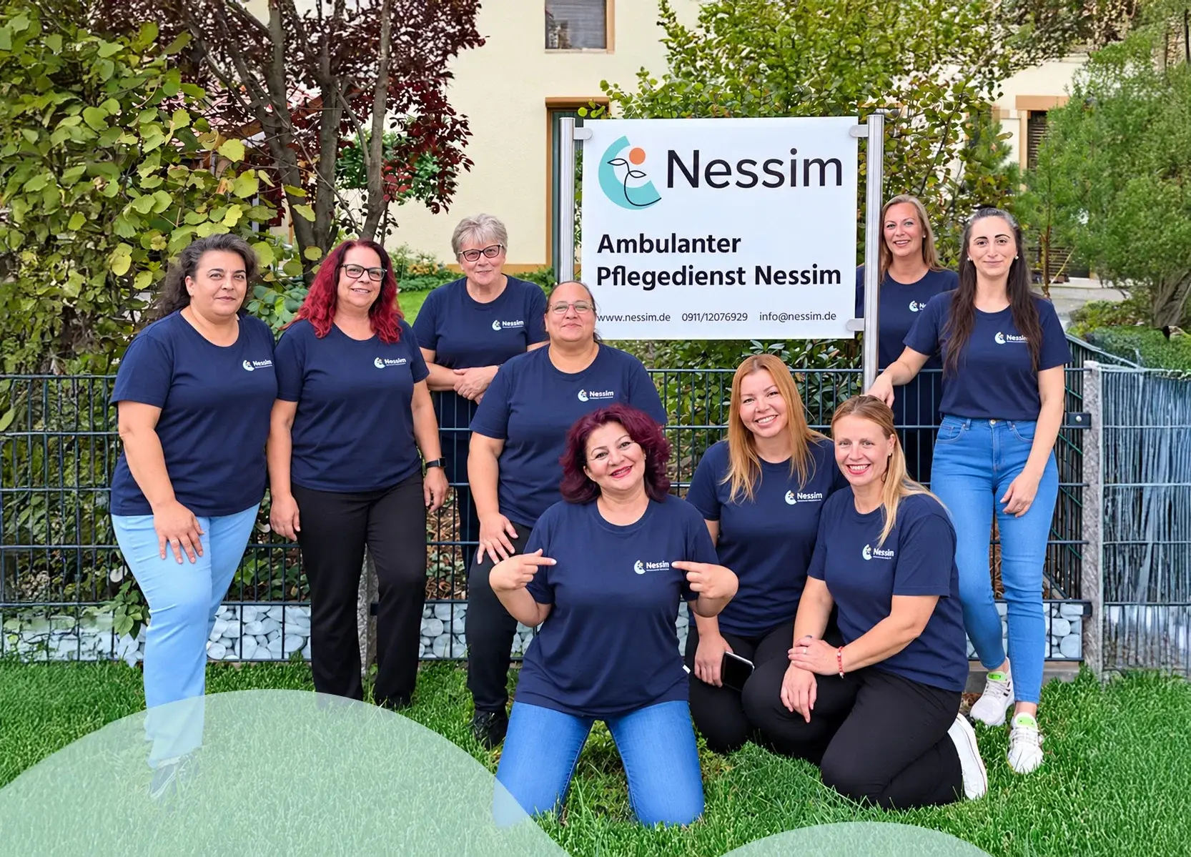 Das Nessim-Team in dunkelblauen Shirts vor dem Schild „Ambulanter Pflegedienst Nessim“
